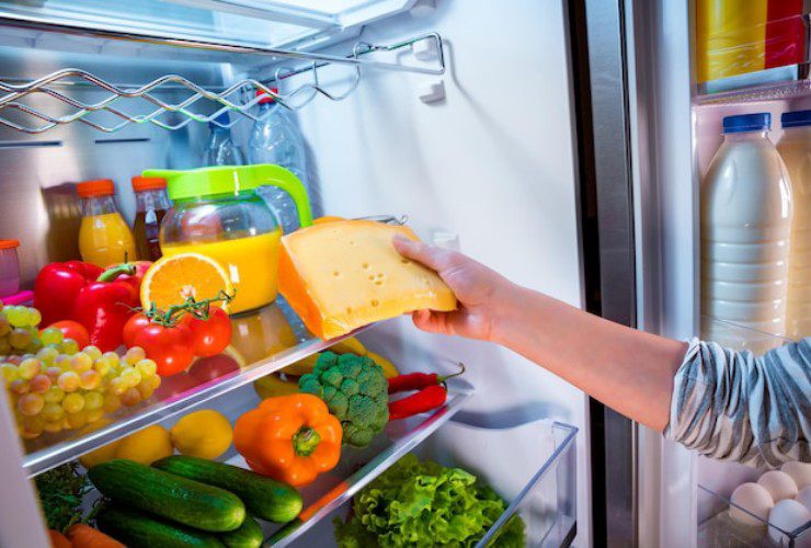 Donna che mette la frutta in frigo