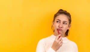 ragazza lava i denti con spazzolino pensando a qualcosa, su sfondo giallo