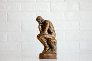 statua del pensatore fotografata di profilo su sfondo bianco